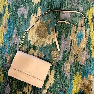 Michael Kors light pink purse with gold chains on part of strap.